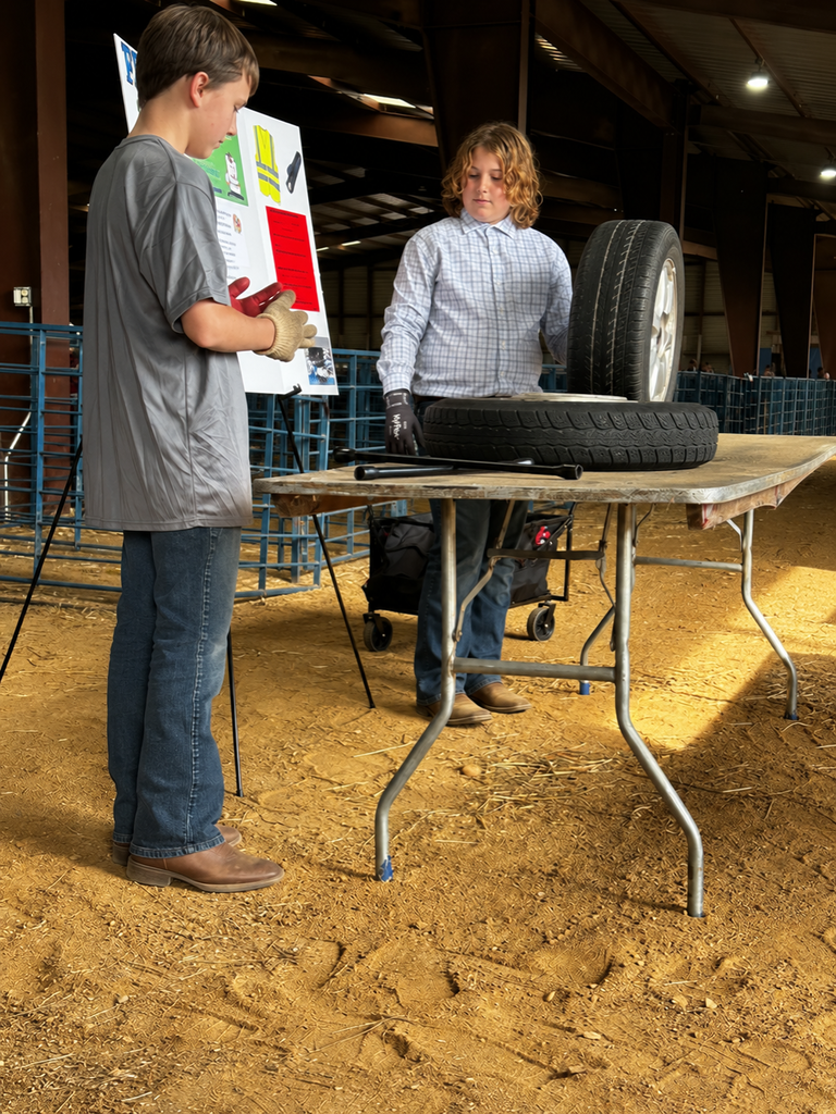 Two CMS FFA students demonstrate a tire-related agricultural project at a table during a competition at the State Fair of Virginia.