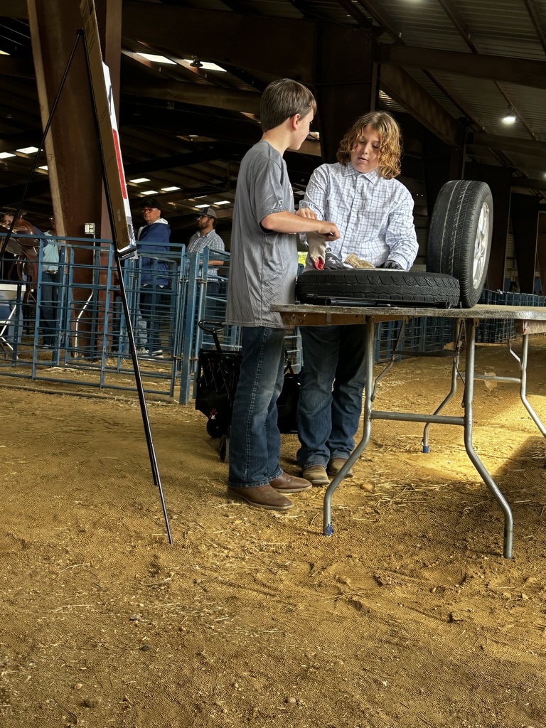 Two CMS FFA students demonstrate a tire-related agricultural project at a table during a competition at the State Fair of Virginia.
