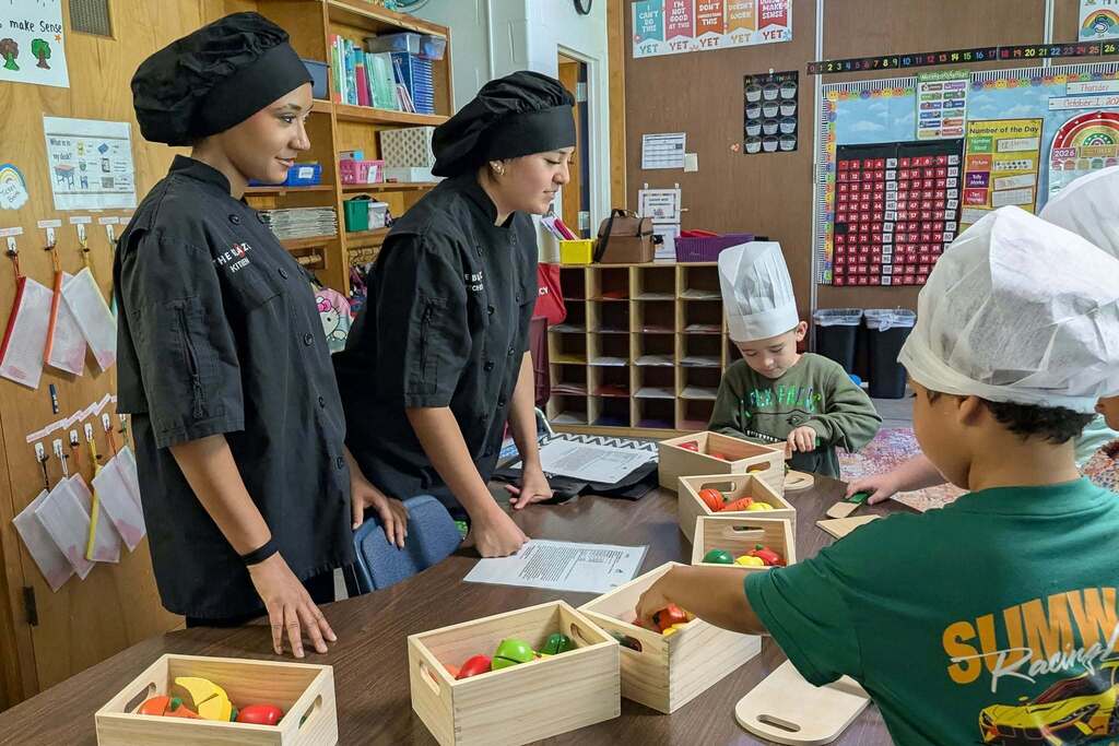 CTEC Culinary students teach first graders about safe knife skills using wooden knives and play food during the Day of Career Exploration.