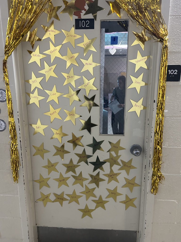 A classroom door decorated with gold fringe and dozens of gold stars featuring students’ names as part of the red-carpet-themed writing celebration.