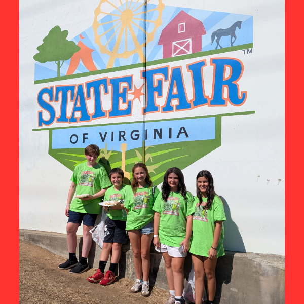 Five Culpeper Middle School FCCLA students wearing matching bright green “FCCLA is a Big Dill” shirts pose together in front of the colorful State Fair of Virginia mural.