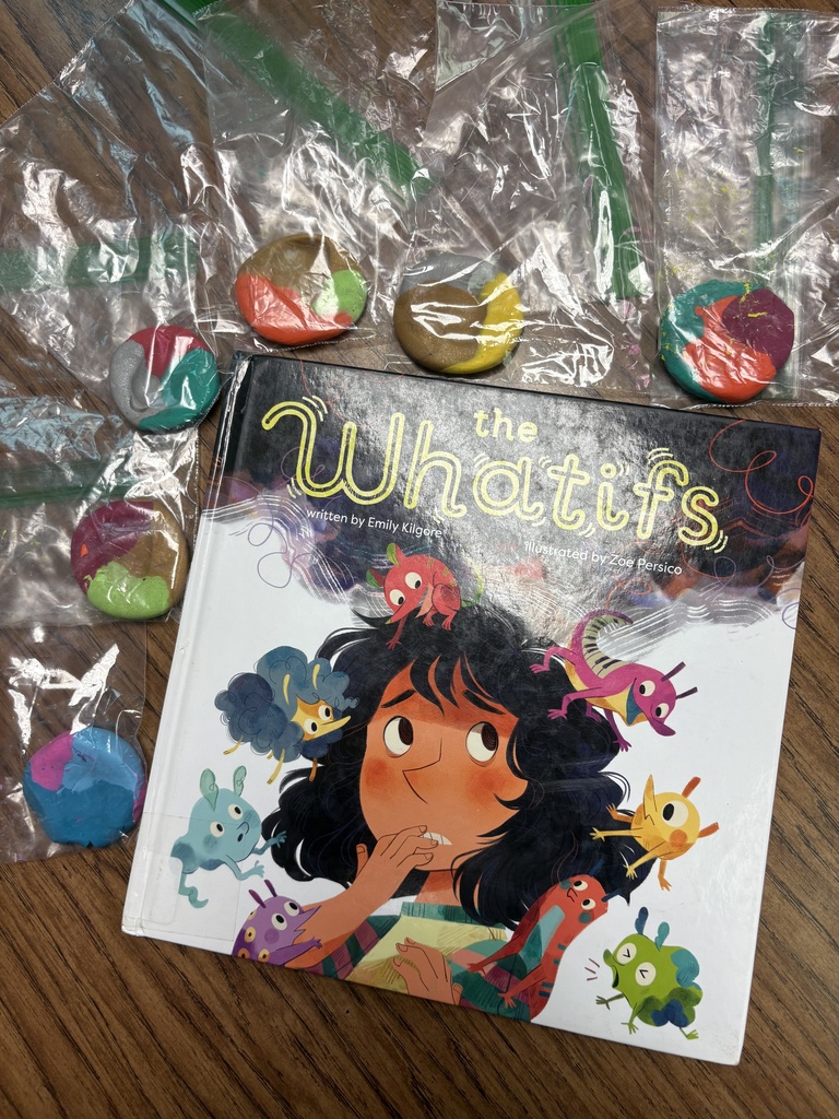 A book titled "The Whatifs" sits on a table surrounded by colorful candies in plastic bags.