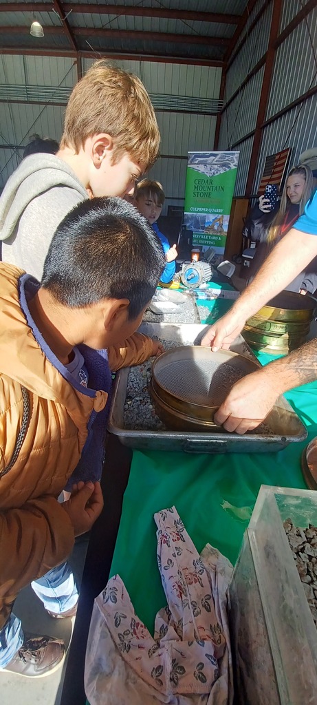People gather around a table inside a warehouse. One person examines a bowl while another hands out food.