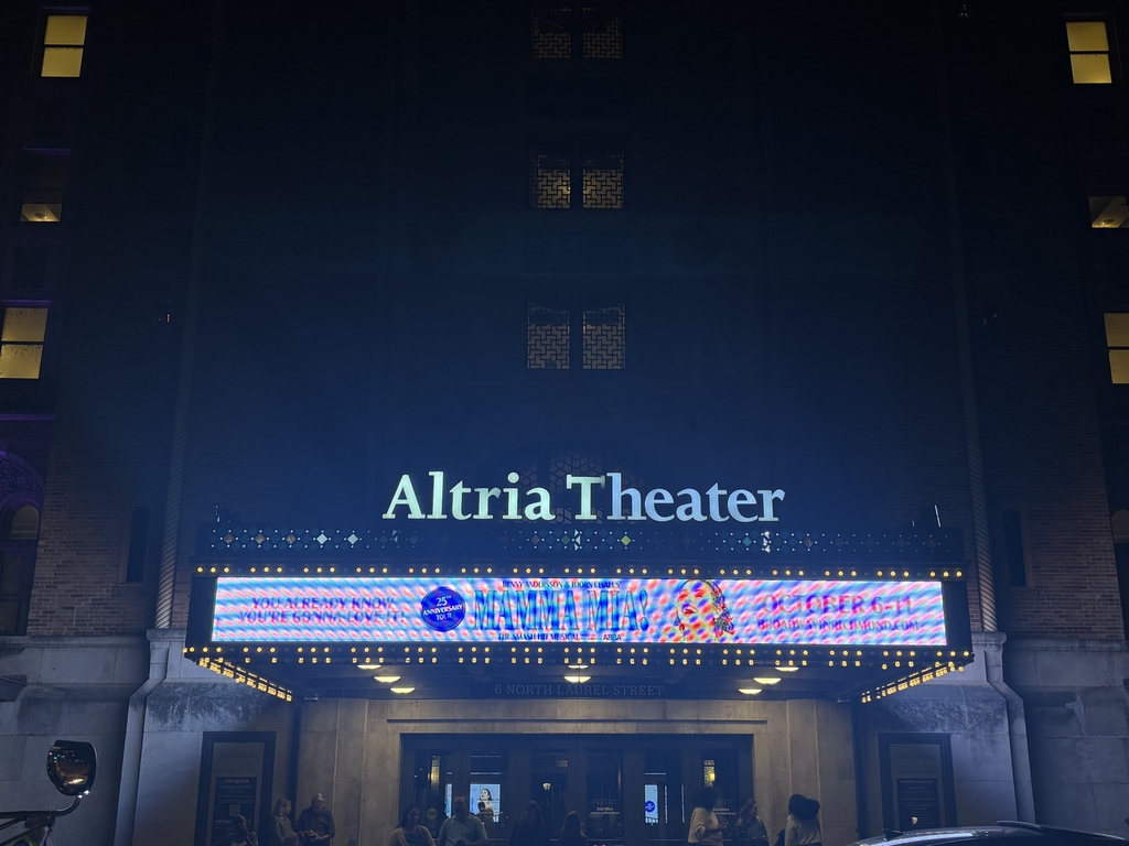 A brightly lit theater marquee at night reads "Altria Theater." Below it, a digital display shows colorful images.