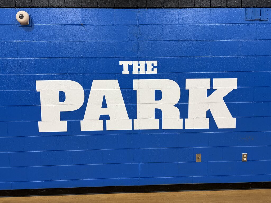 A blue wall with "THE PARK" written in white letters. Below is a small white object, likely a speaker.