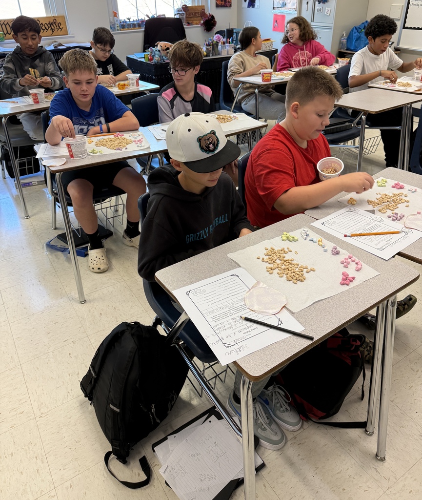 Students in Mrs. Ford’s classroom participate in a hands-on math lesson using Lucky Charms cereal. Students sort marshmallows by shape and color, organize their findings on paper towels, and complete worksheets about ratios while seated at their desks.