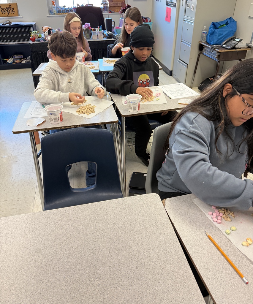 Students in Mrs. Ford’s classroom sort Lucky Charms cereal and colorful marshmallows during an interactive math lesson about ratios. Students work at individual desks, separating marshmallows by shape and color and recording their results on worksheets.