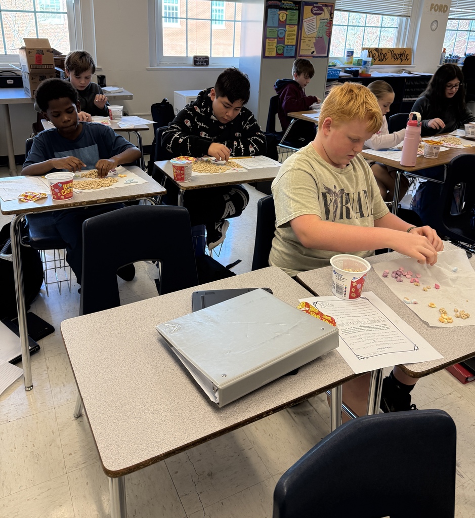 Several students in Mrs. Ford’s classroom work independently on a Lucky Charms math activity. Students separate colorful marshmallows from cereal pieces on paper towels while using worksheets to calculate and record ratios.