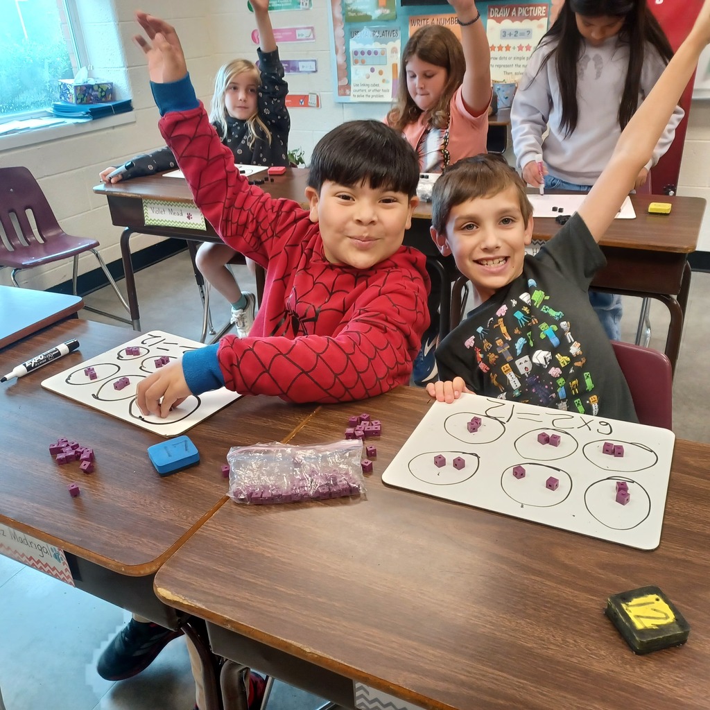 Two children seated at a table, one wearing a red Spider-Man shirt and the other in a black t-shirt.