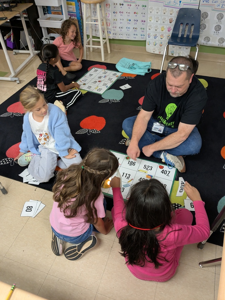 Five children and a man are sitting on a floor, likely engaging in an educational activity.