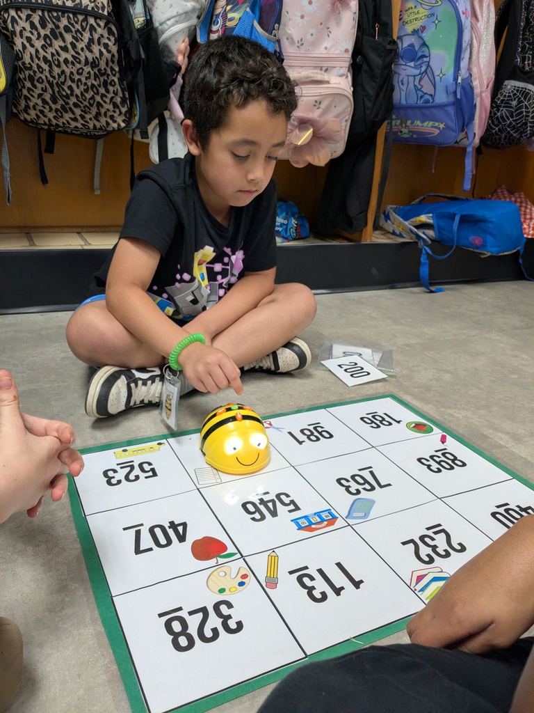 A young child plays a game with a yellow robot on a grid in front of him.