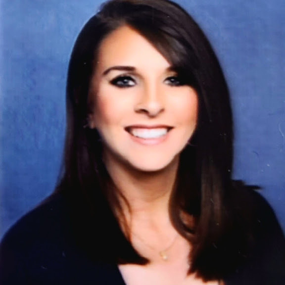 Woman with straight black hair, wearing a black shirt, smiling at the camera with blue background.