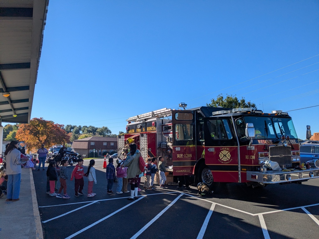 Children in front of a red fire truck, parked in a parking lot with white lines.