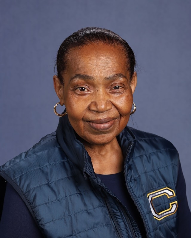 Woman with short hair wearing a dark blue vest with a large C on the back.