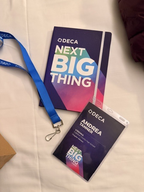 Two colorful books on a blue lanyard lay on a white surface with a brown box.