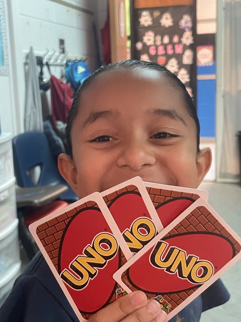 A young boy holds four playing cards in his hands, with a bright red background and yellow text.