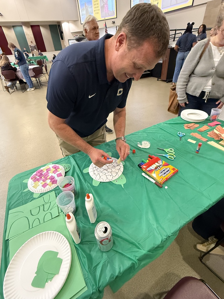 Man wearing blue shirt and khaki pants at a table with a green tablecloth.
