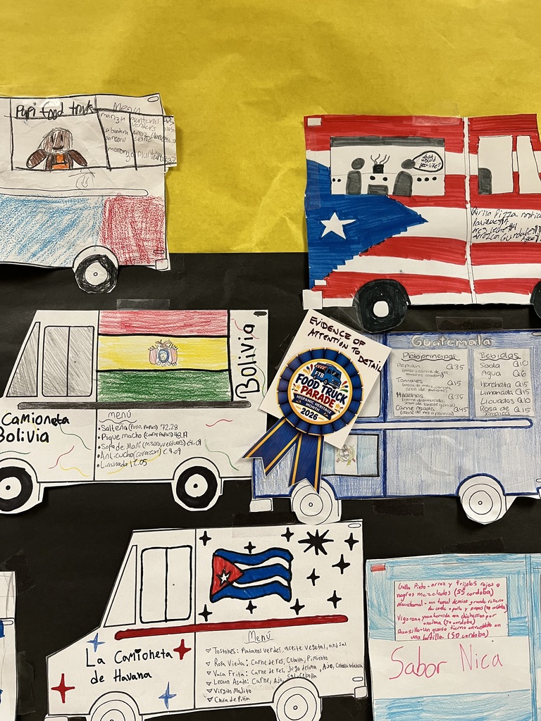 Four paper buses, each with flags and decorations, are displayed on a yellow background. A sign with a ribbon is attached to one bus.