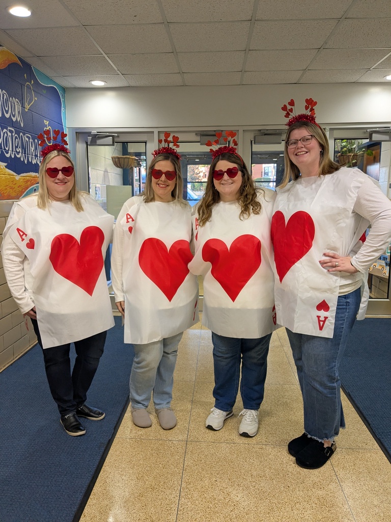 Four women in costume with red hearts on the front and back of their shirts.