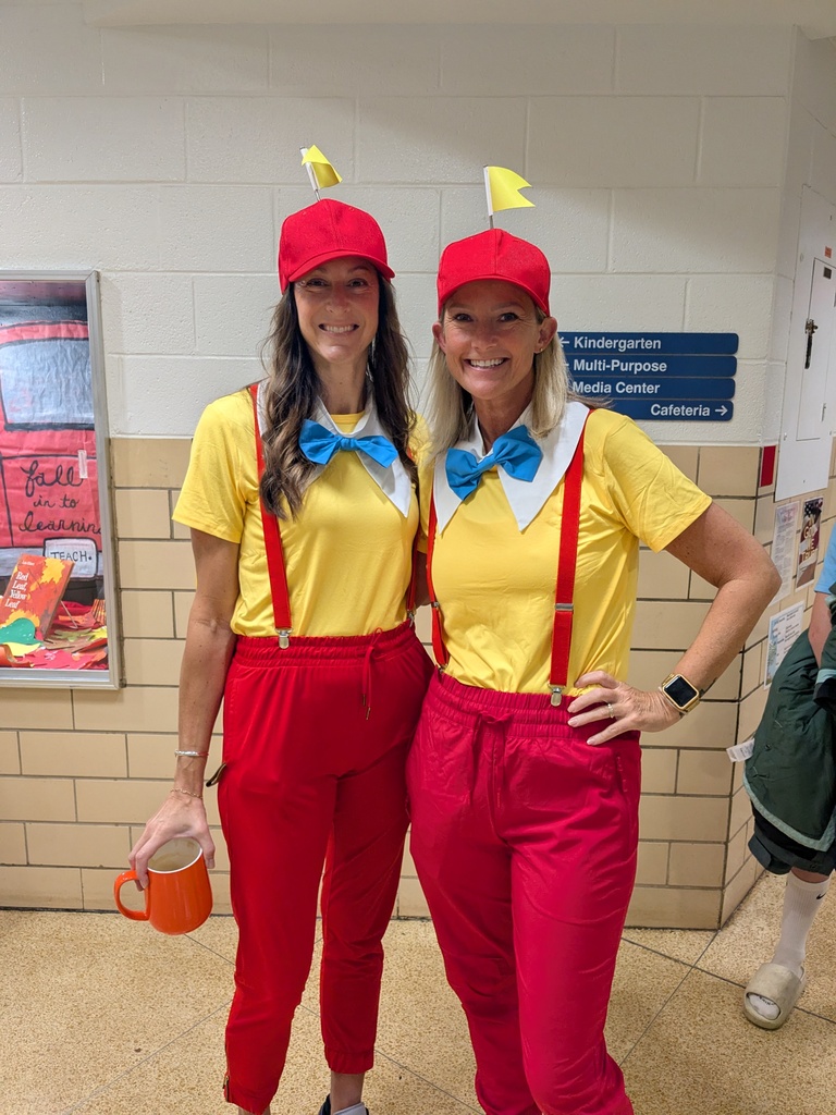 Two women dressed in yellow and red costumes, one holding a mug, stand next to each other.