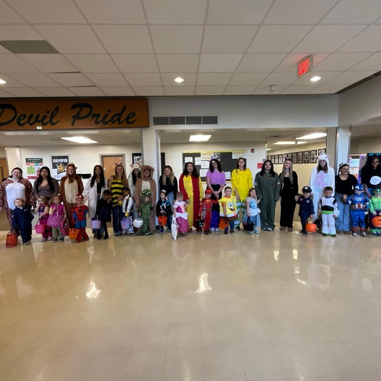 Large group of students in costumes lined up in school hallway with a sign that reads Devil Pride.