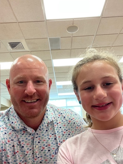 Mr. Slezak poses and smiles for a picture with one of our young female students who is happy to see him.