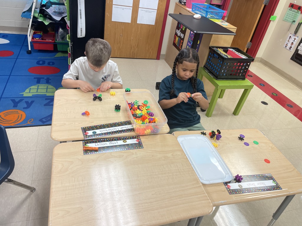 two first grade boys sit at their desks and work with stem building tools to create 3d models