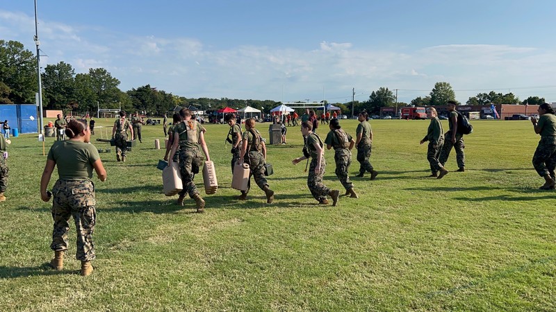 MCJROTC cadets walk across a field in camoflauge on a sunny day