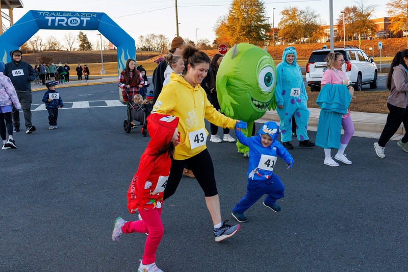 a mom with two little children wearing primary color costumes running