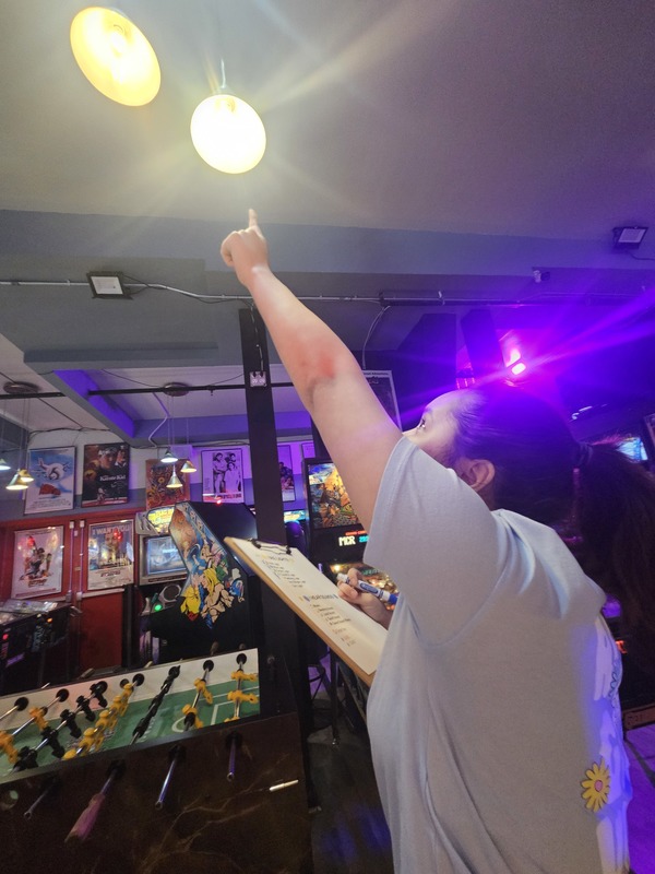 student pointing at light bulb at arcade