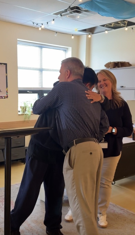 student in classroom hugging principal