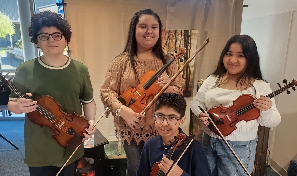 Four students holding string instruments