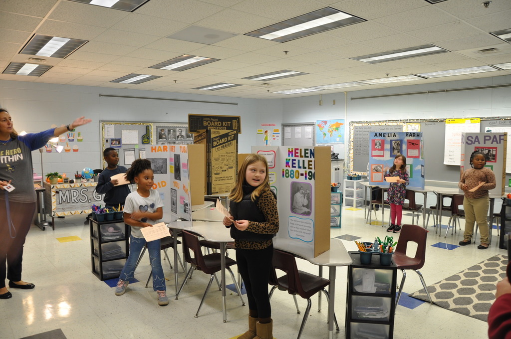 Elementary students stand in front of their prominent figure in hsitory.