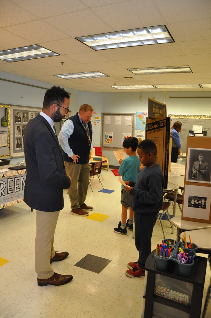 Representative listen to students rehearse their preserntations at the elmentary school