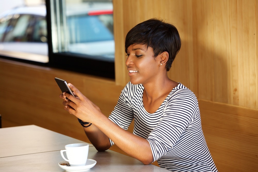 Woman sitting at table with phone & coffee cup