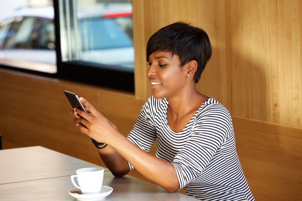 Woman sitting at table with phone & coffee cup