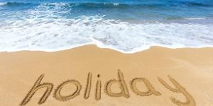"holiday" written in the sand