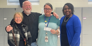 man and woman on left present check to principal and social worker on right