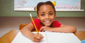 child with pencil writing in school