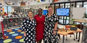 Three women smiling in a library.