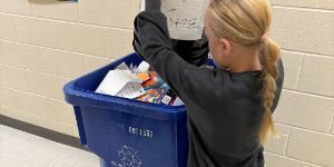 Image showing a fourth grade student on the D7ES Green Team emptying a classroom recycle bin in a larger recycle bin