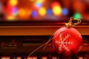 image of red Christmas ball on top of piano keys