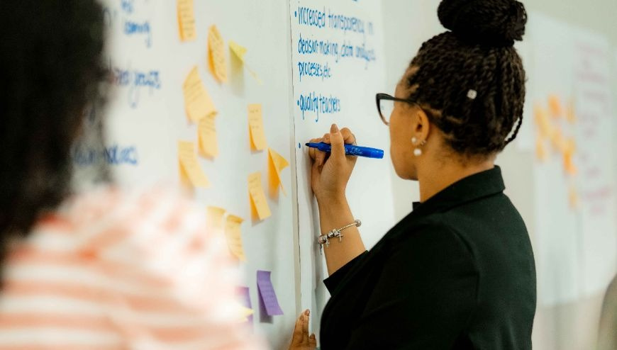 woman writing on chart paper that's on a white board