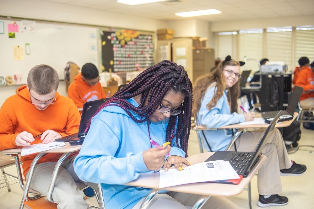 Students writing with laptops on desks