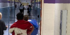 image showing D7ES Green Team members rolling the recycle bin down the hallway as they prepare to empty small classroom and office bins into the larger one