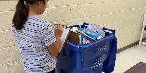 image showing a member of the D7ES Green Team auditing materials from a classroom placed in a recycle bin