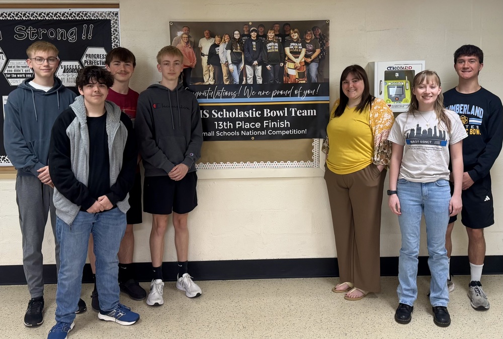 Six of the team members are pictured with their coach next to a banner stating they placed 13th overall.