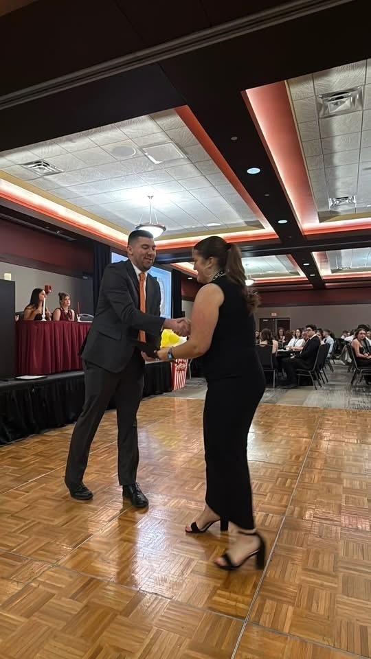 Student si receiving the award from a gentleman. They are shaking hands.