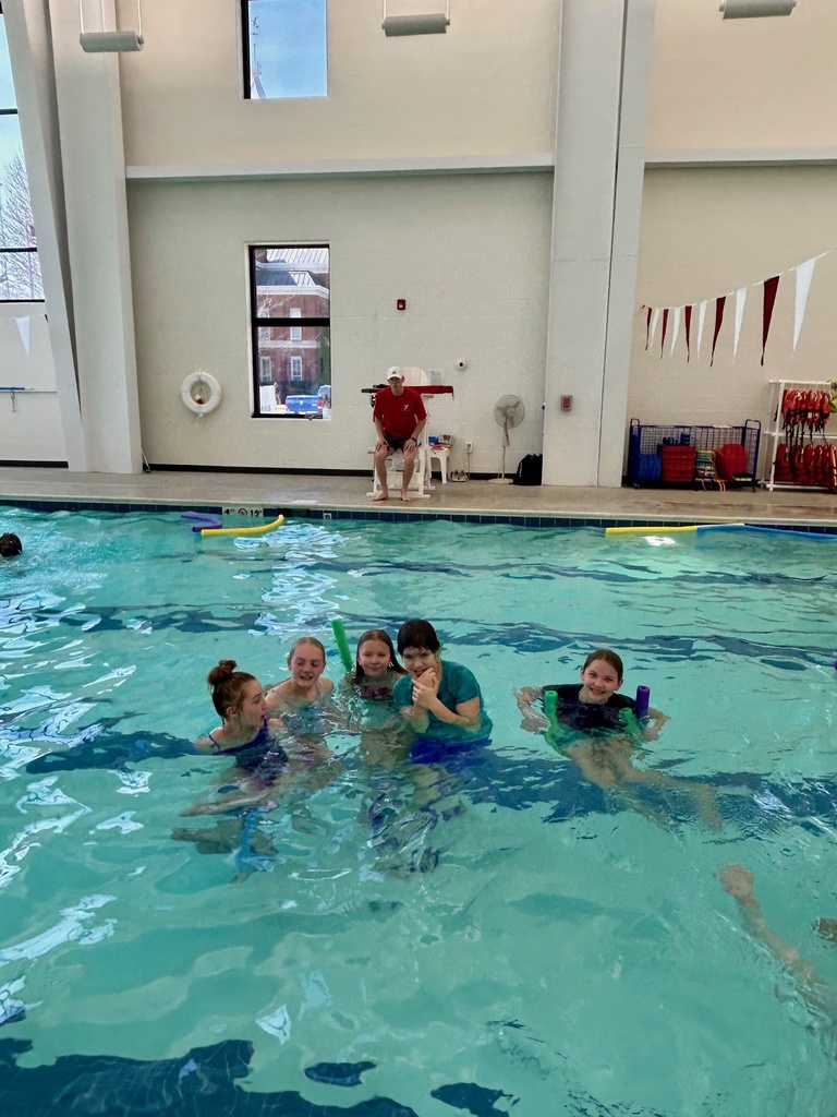 A group of five students are in the pool posing for the camera.
