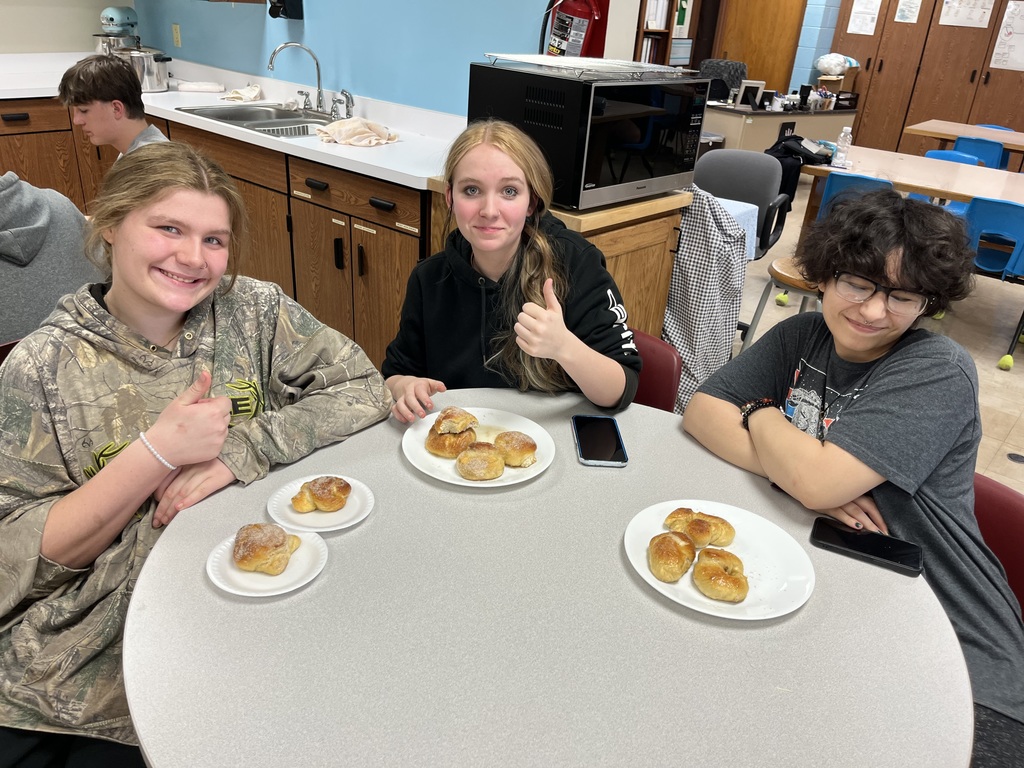 Three students are giving the thumbs up sign to show they love their pretzels!